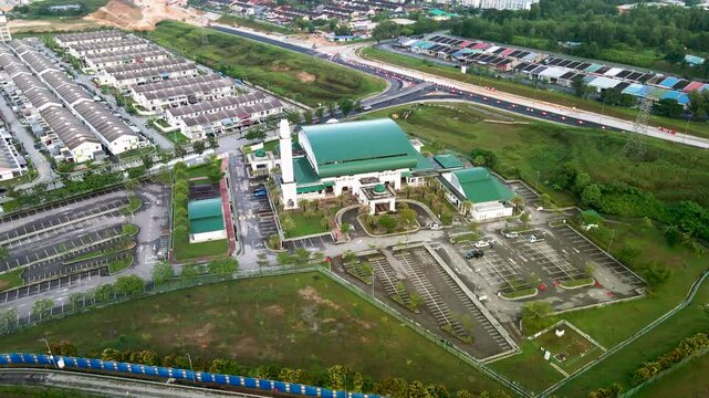 4K aerial view of Masjid Perodua, Bukit Beruntung, surrounded by housing, roads, and greenery, featuring a green roof and spacious parking.