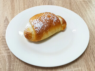 Freshly baked pastry sits on a white plate on a wooden table