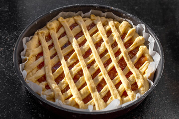 Making a Sweet Jam Pie, topped with a lattice-like woven pastry