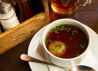 Popular dish of Austrian cuisine is homemade beef soup with liver meatballs, decorated with chopped greenery