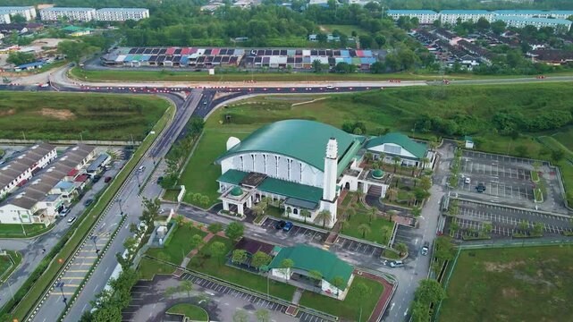 4K aerial view of Masjid Perodua, Bukit Beruntung, surrounded by housing, roads, and greenery, featuring a green roof and spacious parking.