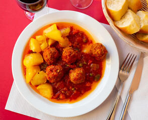 Appetizing smoky spanish Albondigas, meatballs cooked in tomato sauce with potatoes