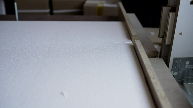 Automated hot wire cutting machinery precisely processing polystyrene foam in industrial manufacturing setting