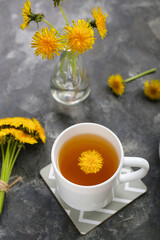 Cup of healthy dandelion tea on grey background
