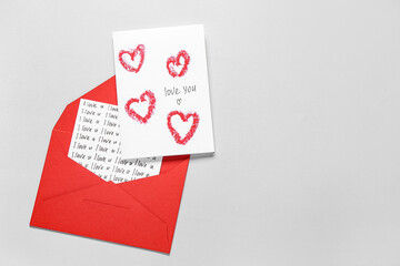 Red envelope and card with text LOVE YOU on grey background. Valentine's Day celebration