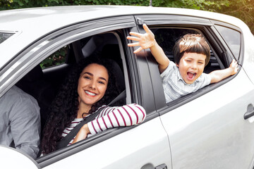 Glad young arabic man and woman driving car, little excited boy with open mouth gesturing, waving...
