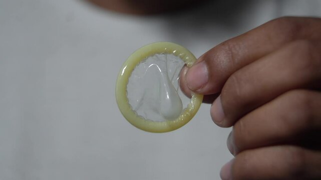 Person opening condom package and showing contraceptive