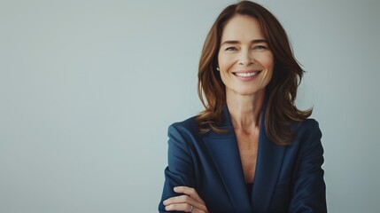 A woman with long hair smiles confidently while dressed in a stylish blazer. The setting is minimalistic and professional, ideal for business engagements