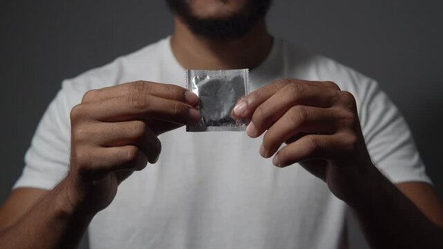 Man holding a condom in white t shirt