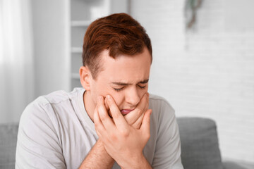 Young man suffering from toothache in room