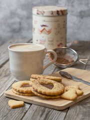 Still life of homemade heart-shaped cookies along with a coffee and kitchen utensils. Romantic snack