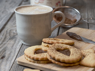 Still life of homemade heart-shaped cookies along with a coffee and kitchen utensils. Romantic snack