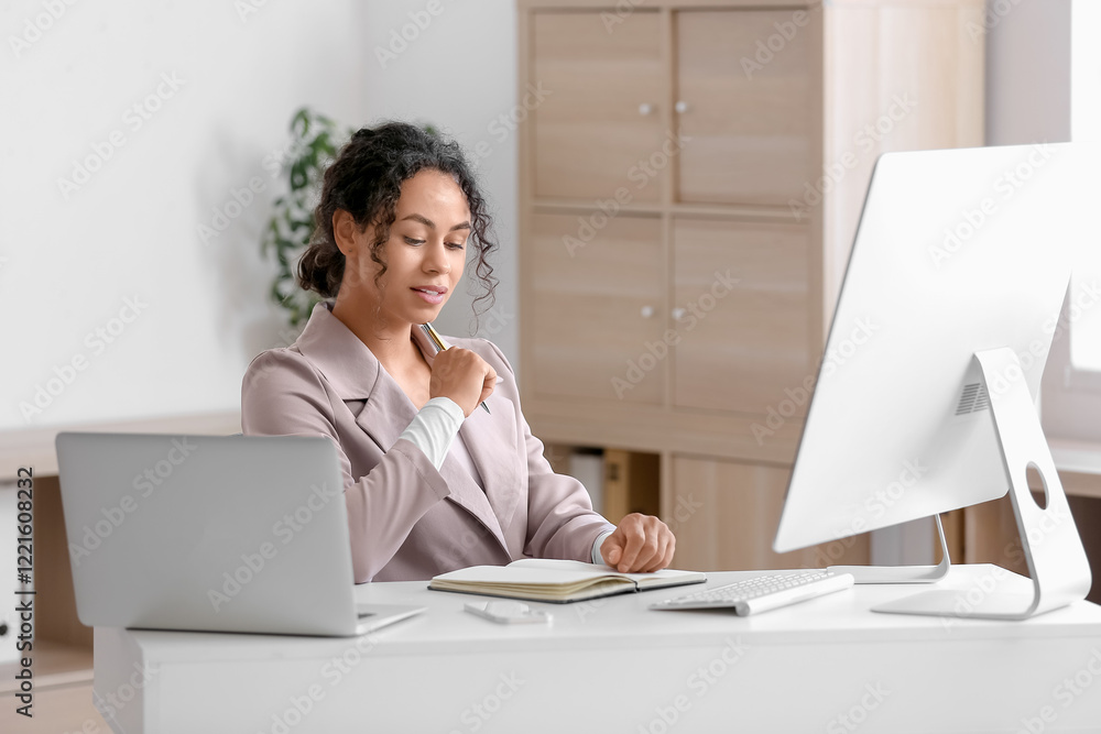Poster young african-american qa engineer with notebook at her workspace in office
