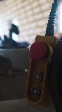 Winch red buttom remote controller in workroom workshop near truck and boat. 4k UHD. Vertical Shot.