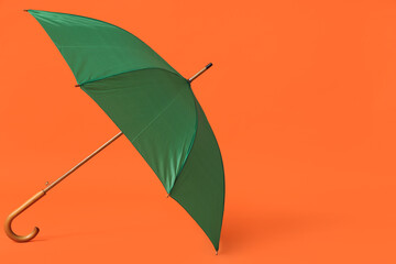 Stylish green umbrella on orange background