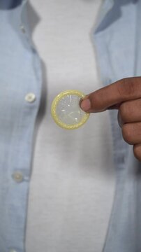 Man opening condom wrapper and showing condom