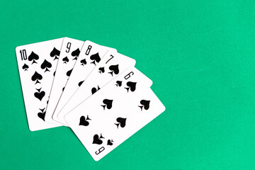 Poker straight flush playing card, top view, copy space, green background