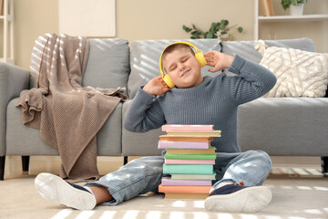 Obraz premium Little boy with headphones and books at home