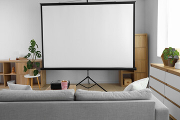 Interior of stylish living room with grey sofa, popcorn and modern projector on coffee table