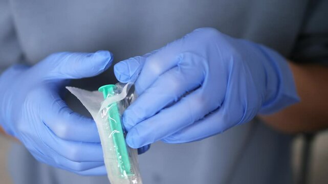 Healthcare worker wearing protective blue gloves prepares sterile syringe, focusing on safe medical injection protocol while ensuring precise handling of sterile syringe and medical equipment. 