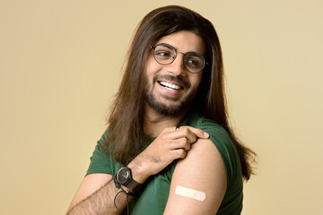 Healthy middle-eastern long-haired young man hipster showing adhesive medical band on his shoulder,...