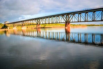 A bridge spans a river with a reflection of the bridge in the water