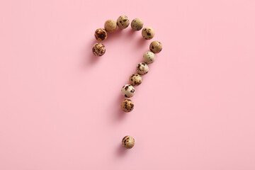 Question mark made of fresh quail eggs on color background
