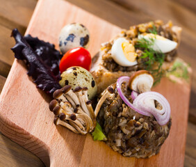 Close-up of tasty pate from button mushrooms with quail egg, onions and greens