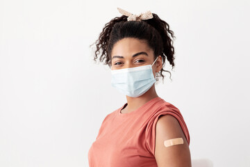 Closeup portrait of young black lady in face mask with medical band on shoulder, african american...