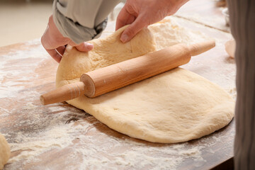 Woman rolling out fresh dough in kitchen