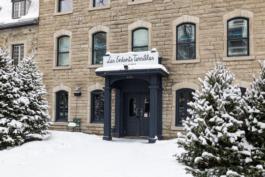 Quebec City, Quebec, Canada, January 26, 2025 - Entrance of Les Enfants Terribles pub in old stone house at 684 Grande-All&eacute;e East seen during a snowy winter morning