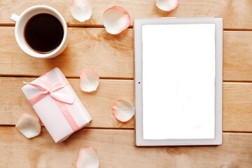 Coffee cup, gift box and white mockup tablet on wooden background. Valentines day background. Copy space for the text