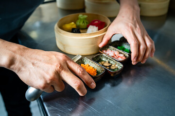 Chef organizing condiments and bamboo steamer with colorful dumplings - professional preparation