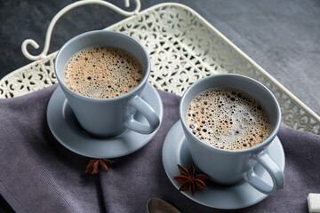 Cups of hot coffee and star anise on black background