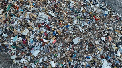 Aerial close-up of a landfill with a chaotic mix of waste, including plastic, wood, and discarded...