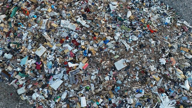 Aerial close-up of a landfill with a chaotic mix of waste, including plastic, wood, and discarded materials. The polluted site highlights environmental damage and excessive waste accumulation.