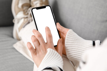 Young woman using blank mobile phone on sofa at home, closeup
