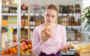 Young girl buyer chooses fresh cheese in grocery store