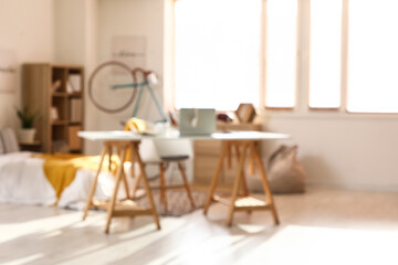 Blurred view of teenager's room with bed, workplace and bicycle