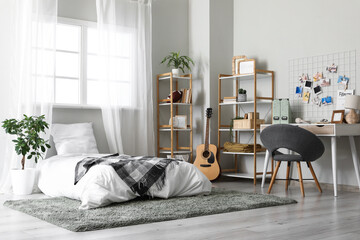 Interior of teenager's room with bed, workplace and shelf units
