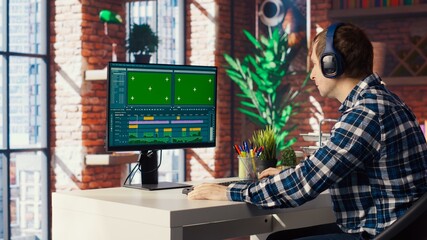 Video editor selecting key frames to use while doing video montage, working from home on green...