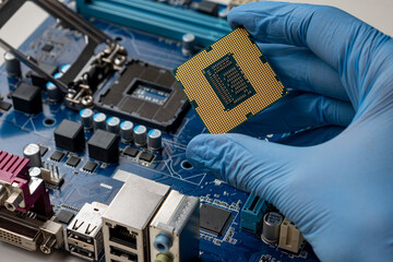 Gloved hand holding microprocessor near the motherboard.
