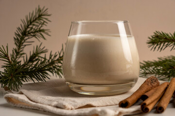 Traditional Christmas drink Eggnog with cinnamon on white table. Hot beverage for winter holidays.