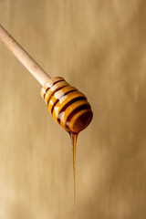 Honey dripping from honey dipper on yellow background.