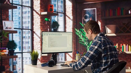 Man in home office looking at UI on PC screen, typing and executing programming code. Coding application UI used by IT developer writing and testing code in modern workspace, camera A