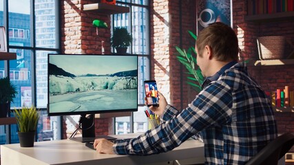 Man at home having fun looking at social media reels done by online content creators. Employee taking break from work to use mobile social network app, screensaver activating on PC, camera A