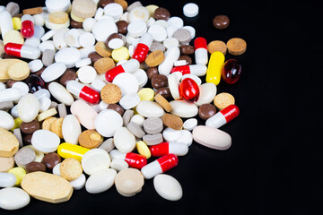 Pills of different shapes and sizes on a black background