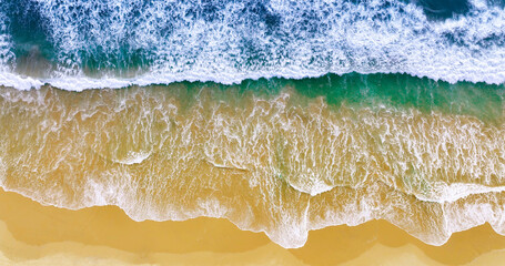 Blue ocean wave on yellow sandy beach. Sea waves and sand the summer background. Summer seascape beautiful waves, blue sea water. Top view from drone. Sea aerial view, tropical nature background.