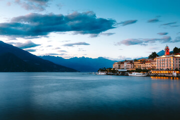 Naklejka premium Lake Como reflecting the charming village of Bellagio, with a dramatic sky filled with vibrant colors at sunset, creating a breathtaking scene in Lombardy, Italy