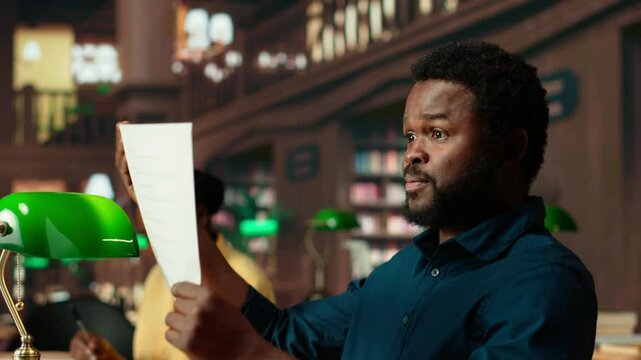 Black student rehearsing lines from the script for drama school course, auditioning for a theatre play competition. Young scholar reciting dialogue at the campus library. Camera B.